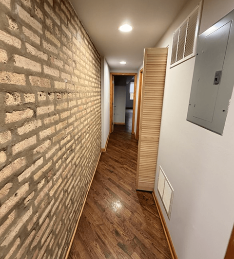 A long hallway with a brick wall on the left and wooden slats on the right.