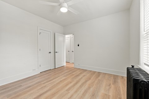 A room with a ceiling fan and a radiator on the floor.