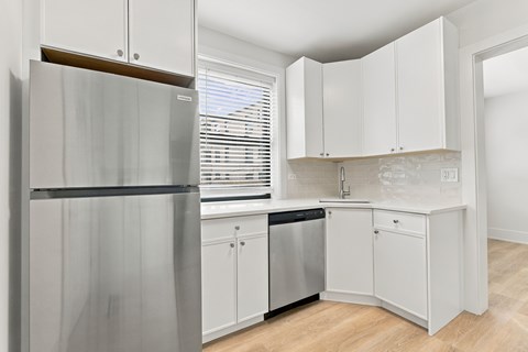 A kitchen with white cabinets and a stainless steel refrigerator.