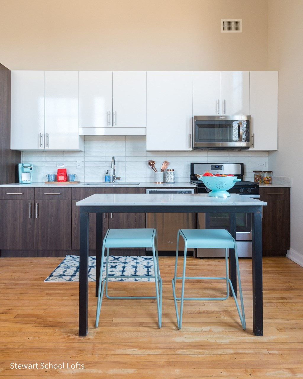 a kitchen with white cabinets and a blue island with two blue chairs
