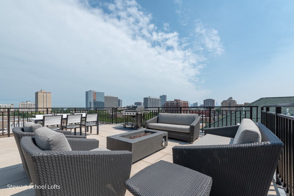 a rooftop deck with furniture and a city in the background