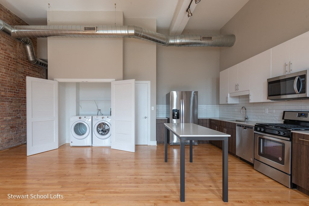 an empty kitchen with a washer and dryer and a stainless steel table