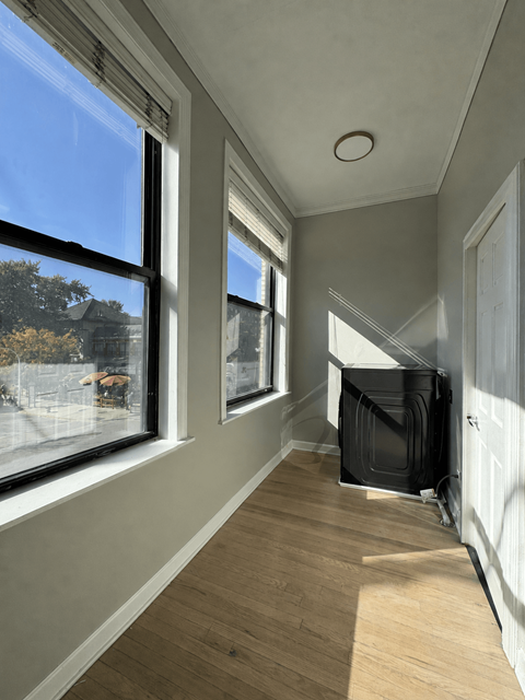 A long hallway with a window on the left and a door on the right.