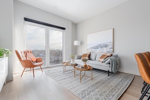 A living room with a grey couch, a wooden chair, and a coffee table.