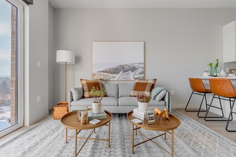 A living room with a grey couch, a coffee table, and a large painting on the wall.