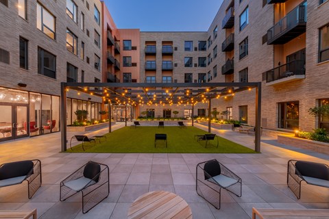 A patio with chairs and a table is surrounded by apartment buildings.