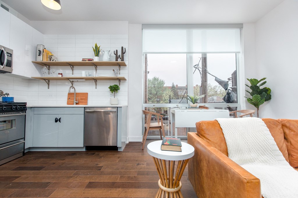 a living room with a couch and a kitchen with a large window