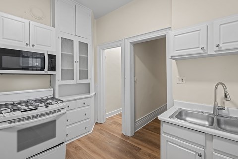 A kitchen with white cabinets and appliances.