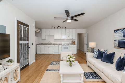 A living room with a white couch and a ceiling fan.