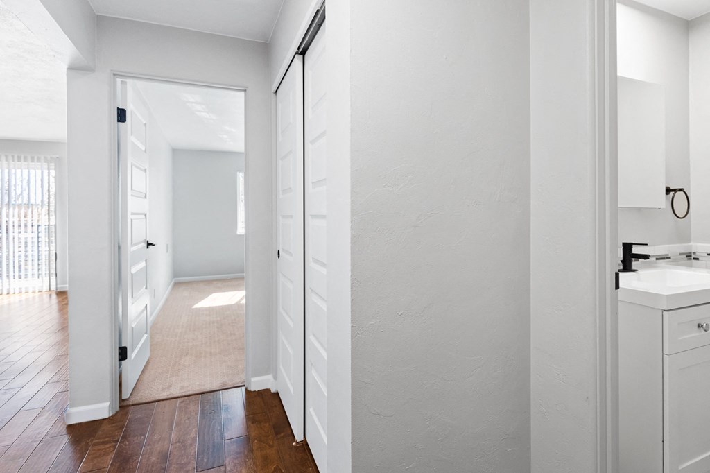 a bedroom with a door to a hallway with a sink and a mirror