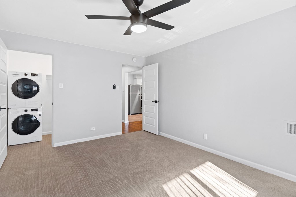 a white room with a washer and dryer in it and a ceiling fan