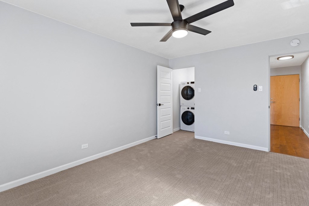 a living room with a ceiling fan and a door to a laundry room