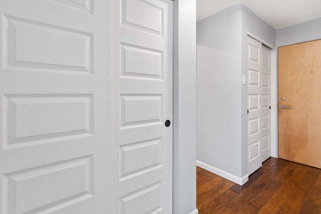 an empty room with white doors and a door to a closet