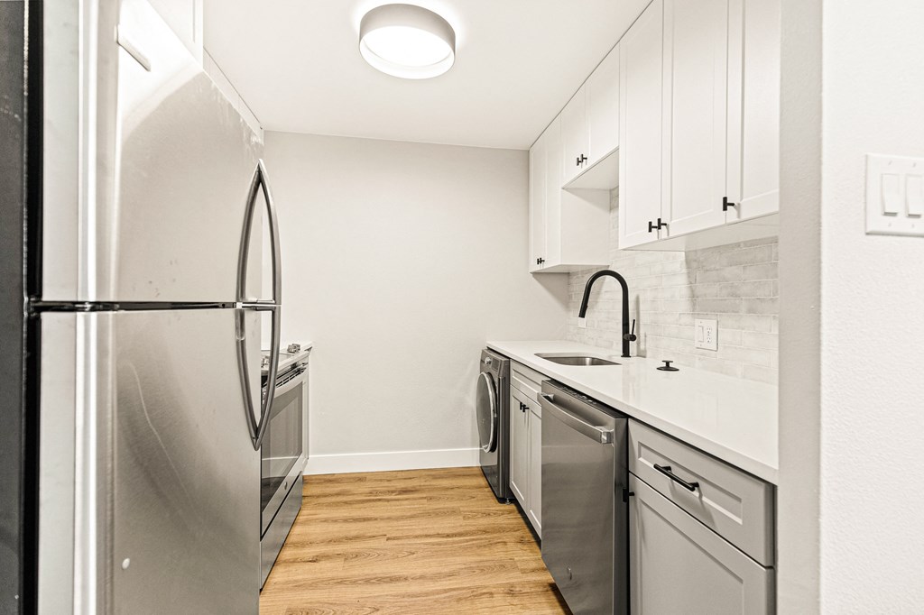 a renovated kitchen with stainless steel appliances and white cabinets
