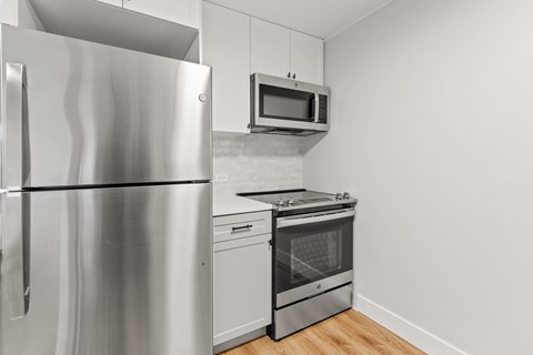 A kitchen with a stainless steel refrigerator and microwave above the stove.