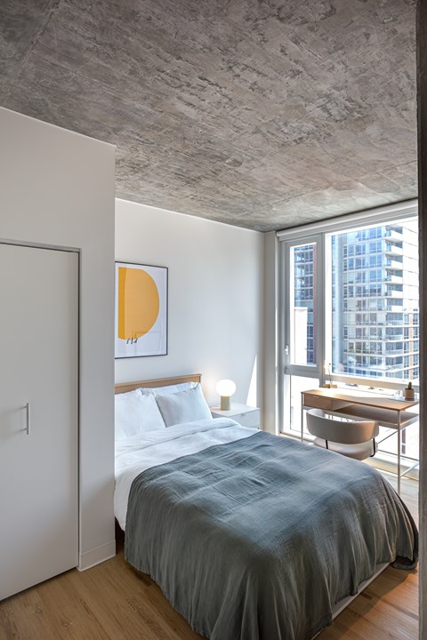 A bedroom with a bed, desk, and chair.