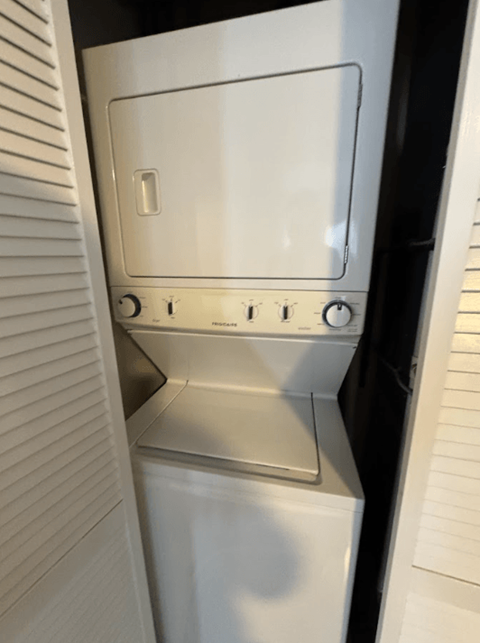 A white dishwasher is shown in a narrow space between two walls.