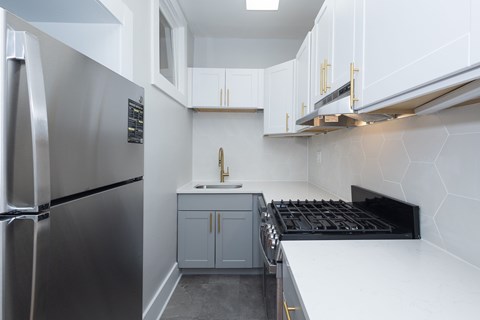 A modern kitchen with a stainless steel refrigerator and a black stove top.