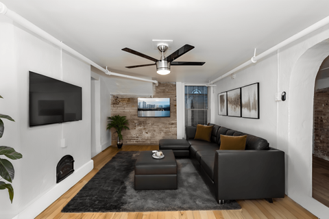 A modern living room with a black leather sofa and a flat screen TV mounted on the wall.