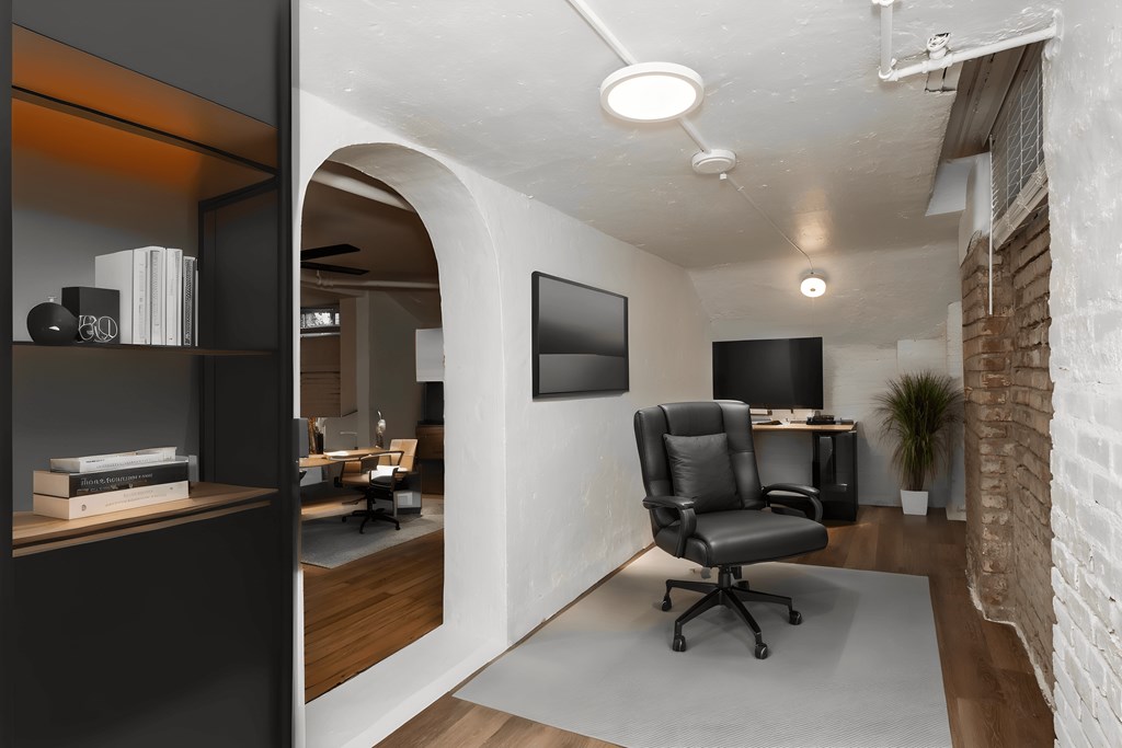 a room with a desk and a chair and a tv on the wall