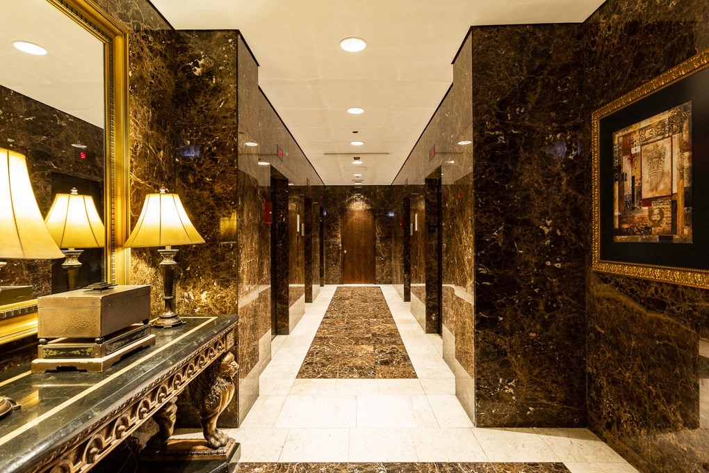 the hallway of a hotel lobby with marble walls and a long hallway with a carpet