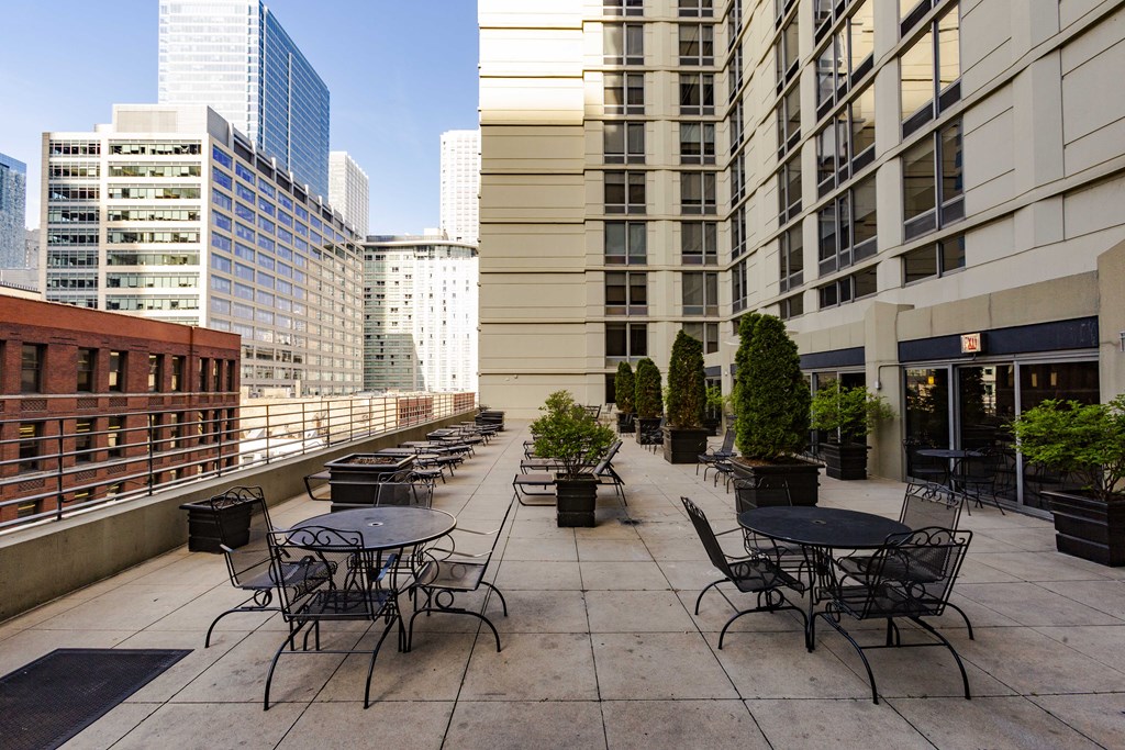 an outdoor patio with tables and chairs on a balcony in the city
