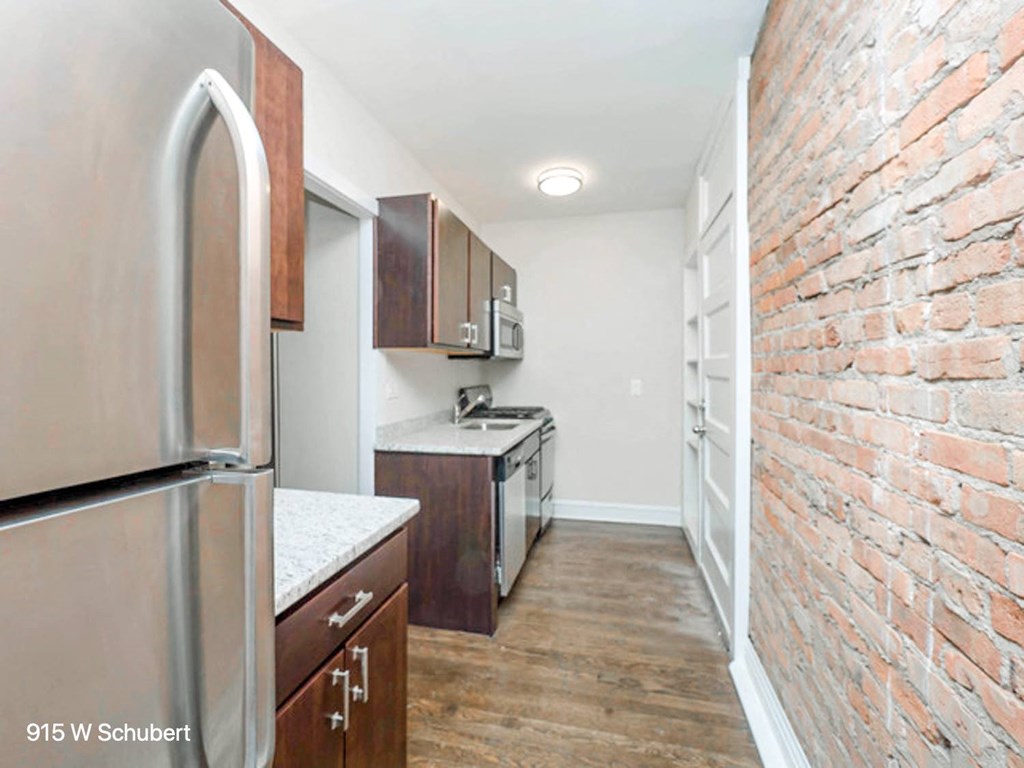 a renovated kitchen with a brick wall and stainless steel appliances
