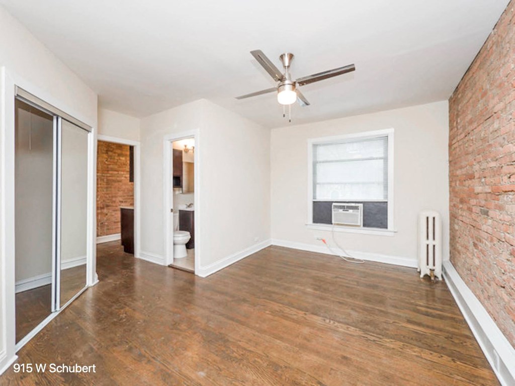 an empty living room with a ceiling fan and a window