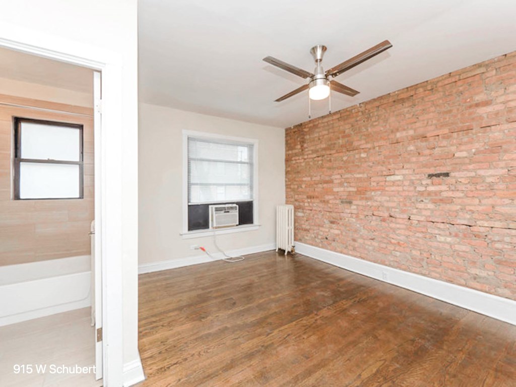 an empty living room with a brick wall and a ceiling fan