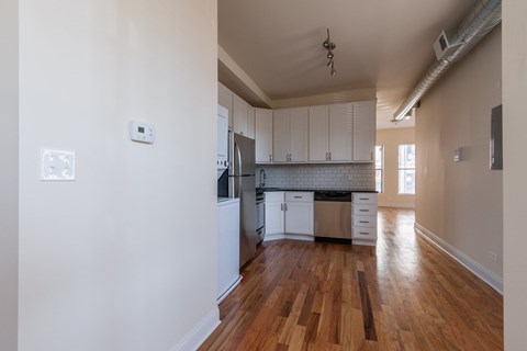 A kitchen with white cabinets and a wooden floor.