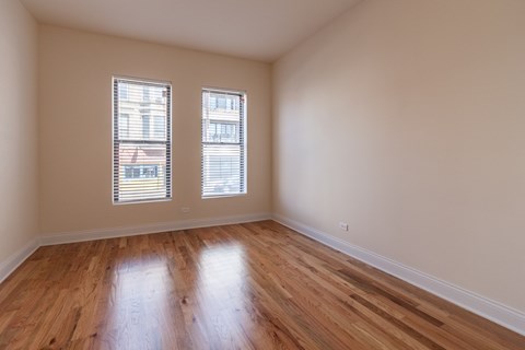 A room with wooden floors and two windows.