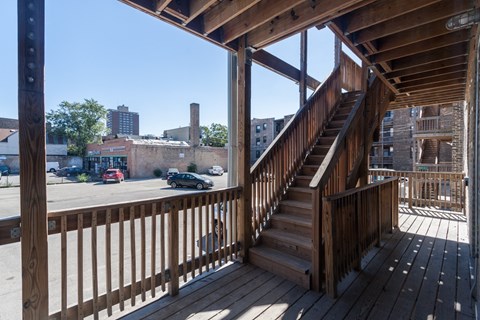 A wooden staircase with a railing is in the foreground of a city street.