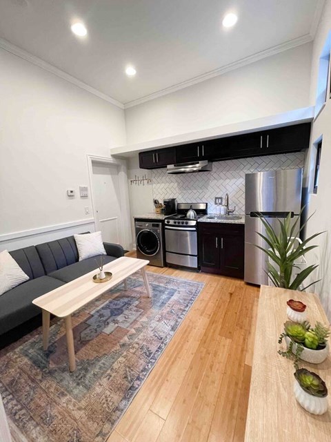 A modern kitchen with a grey sofa and wooden table.