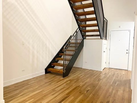 A wooden staircase with a metal railing leads up to a door.
