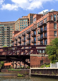 a bridge over a river in front of tall buildings