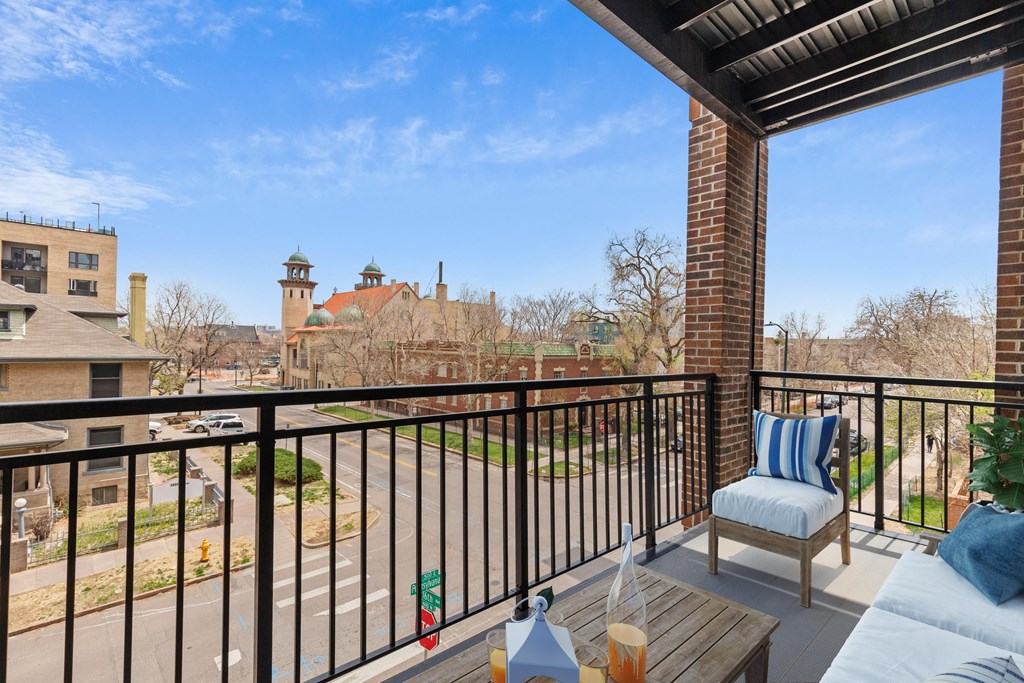 a balcony with a couch and a chair and a view of the city