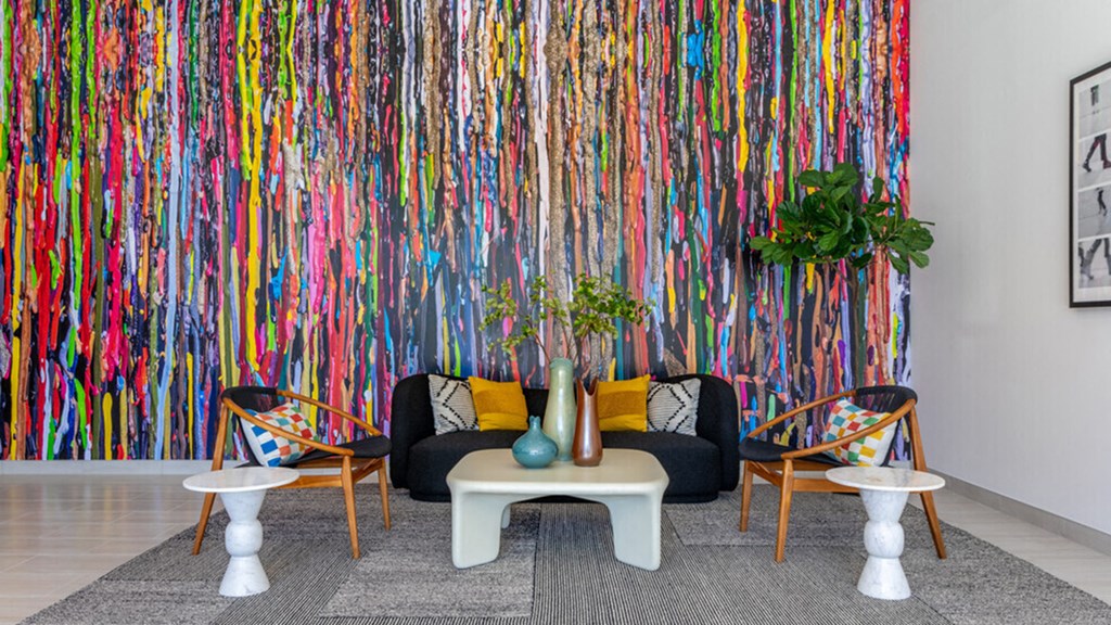 a living room with a couch and chairs and a colorful wall with dripping paint
