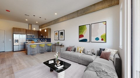 a living room with a couch and a table in front of a kitchen