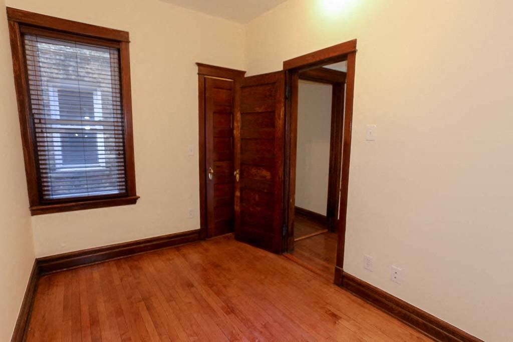 an empty room with wooden floors and a closet and a window