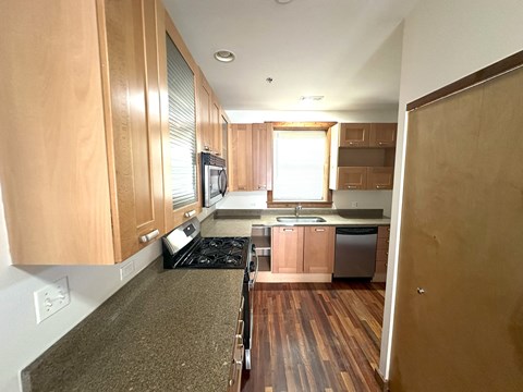 a view of a kitchen with wood cabinets and black counter tops