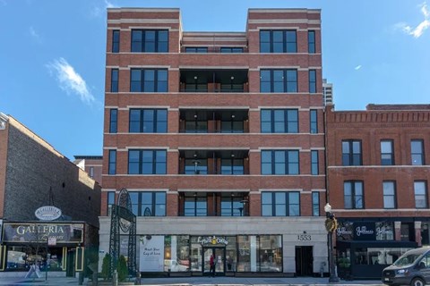 A tall red brick building with a balcony on the top floor.