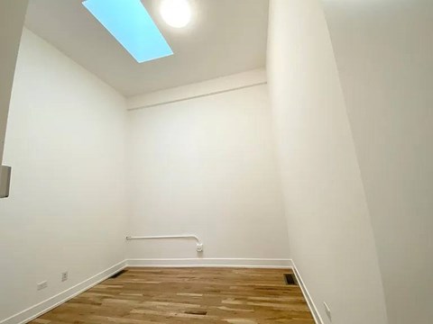 A room with a skylight and wooden flooring.