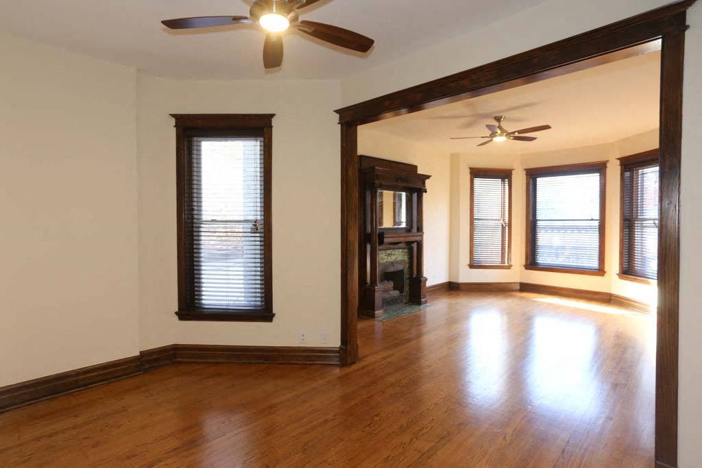 an empty living room with wood floors and a ceiling fan