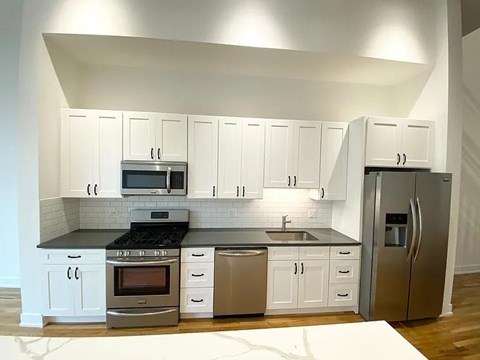A modern kitchen with stainless steel appliances and white cabinets.