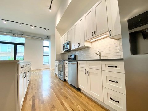 A kitchen with white cabinets and wooden floors.