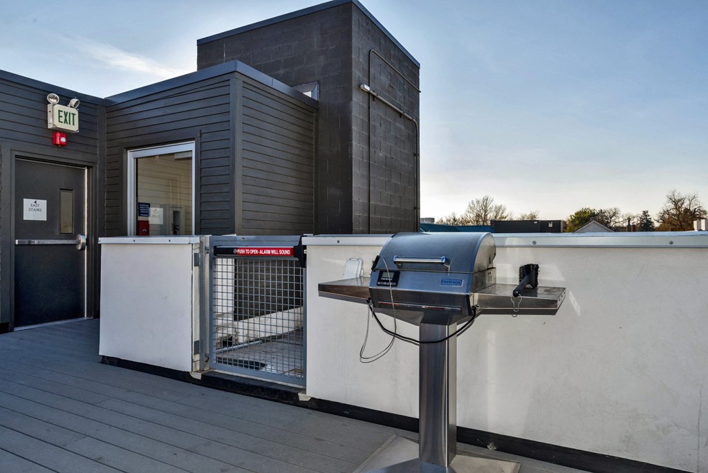 a grill on a patio next to a building with a dog gate
