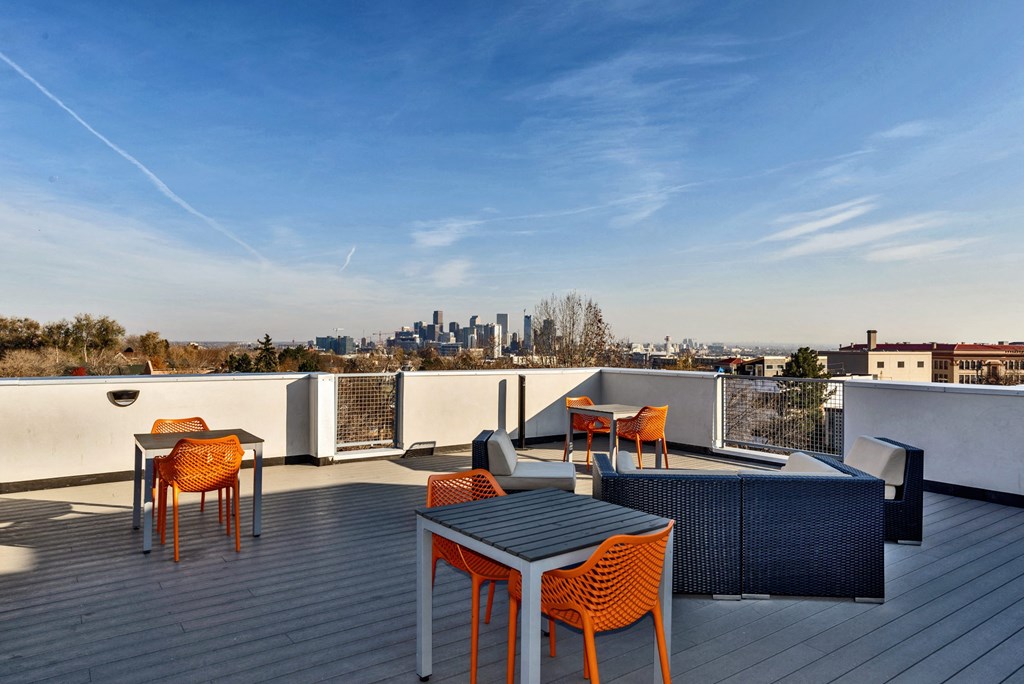 a rooftop patio with tables and chairs and a view of the city