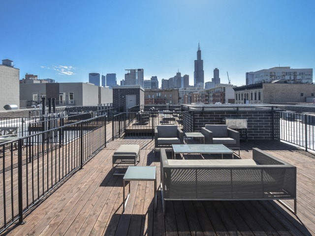 the top of a roof deck with picnic tables and a view of the city