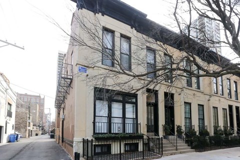 A beige building with black railings and a black awning.