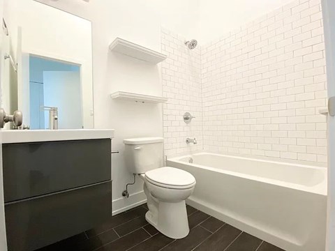 A white toilet sits in a bathroom next to a bathtub.